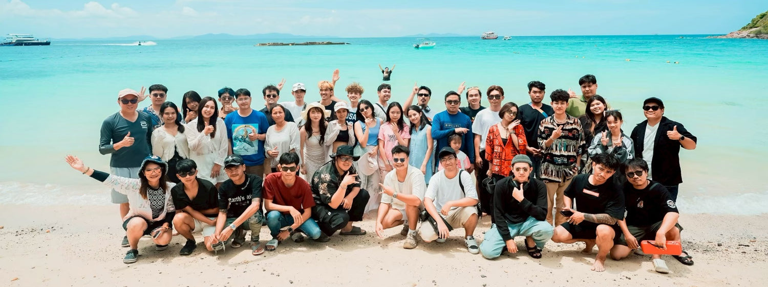 HUGTEAM posing for a photo on a beach with clear blue water and sky.